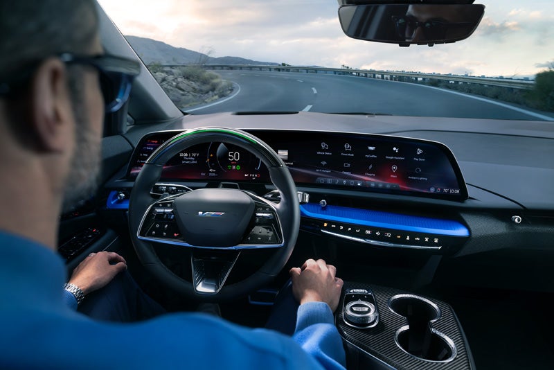 Front View of the 2026 OPTIQ-V Driving Through the Dusk Utilizing its Headlights | AutoGrupo Cadillac in TOA BAJA PR